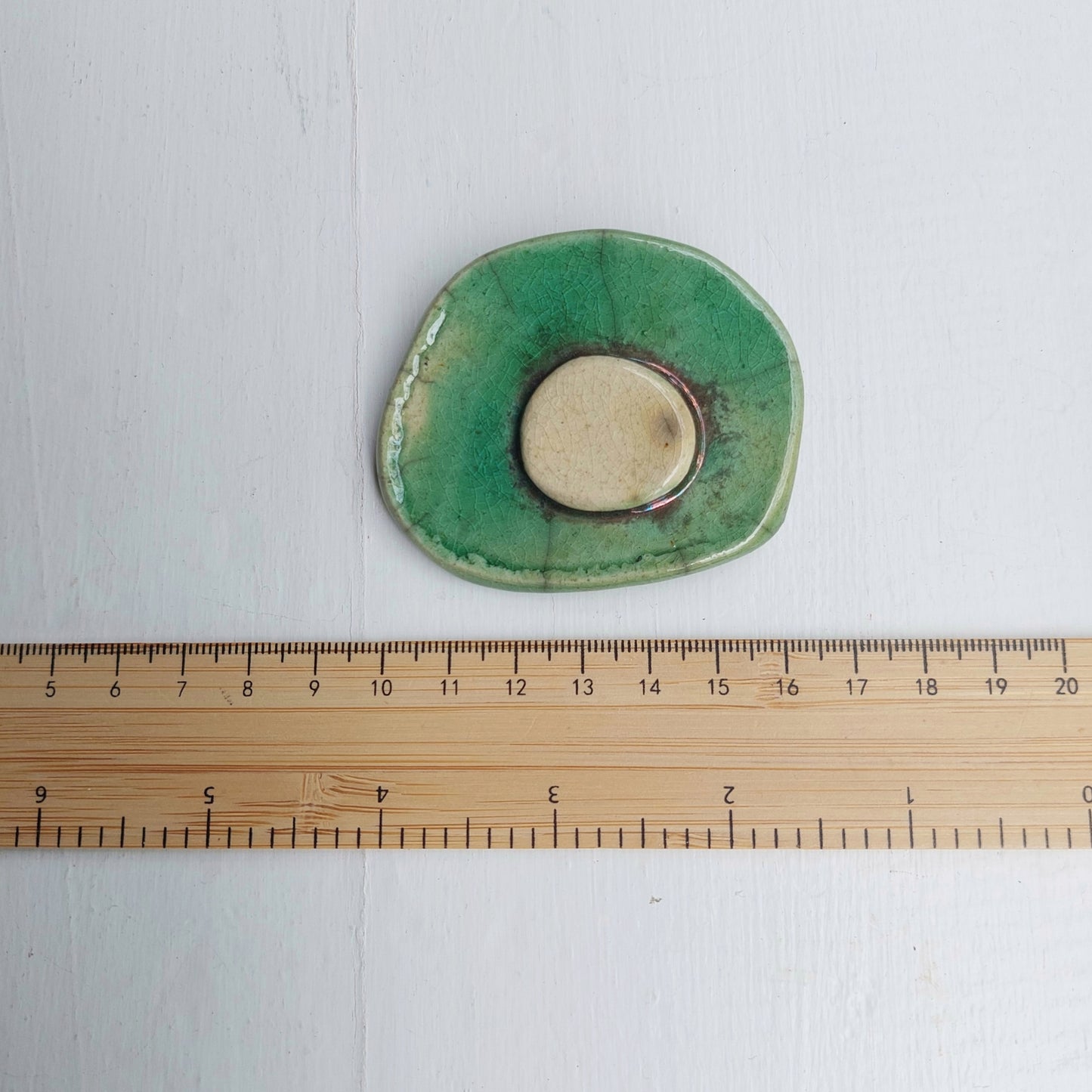 Spilla verde e oro in ceramica verde e bianca Raku con base in metallo.