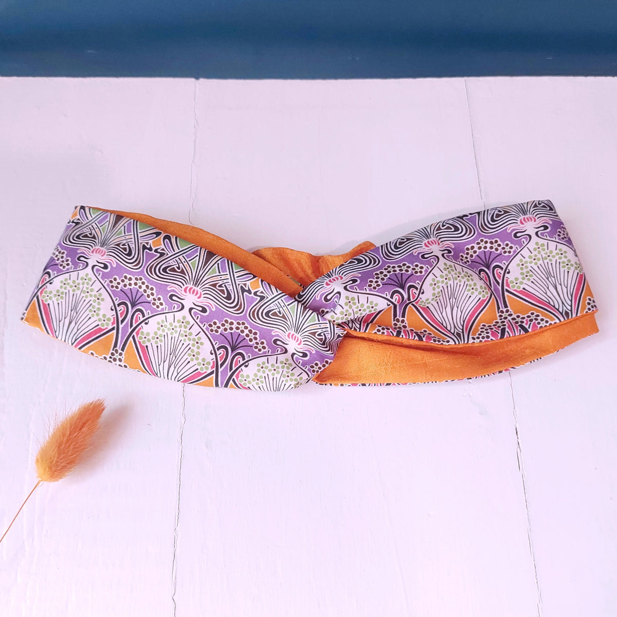 Fascia capelli in cotone bianco, arancione, viola e nero e seta arancione con chiusura ad elastico.