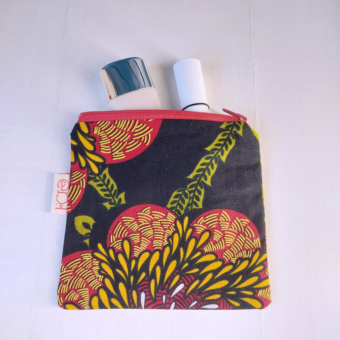 Pochette in cotone con decorazione floreale nero, verde, rosso e giallo, foderata.