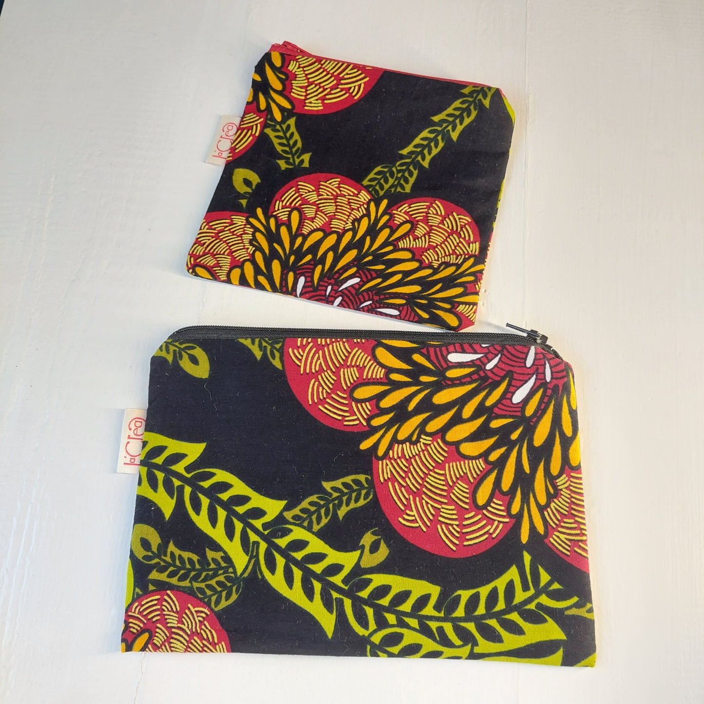 Pochette in cotone con decorazione floreale nero, verde, rosso e giallo, foderata.