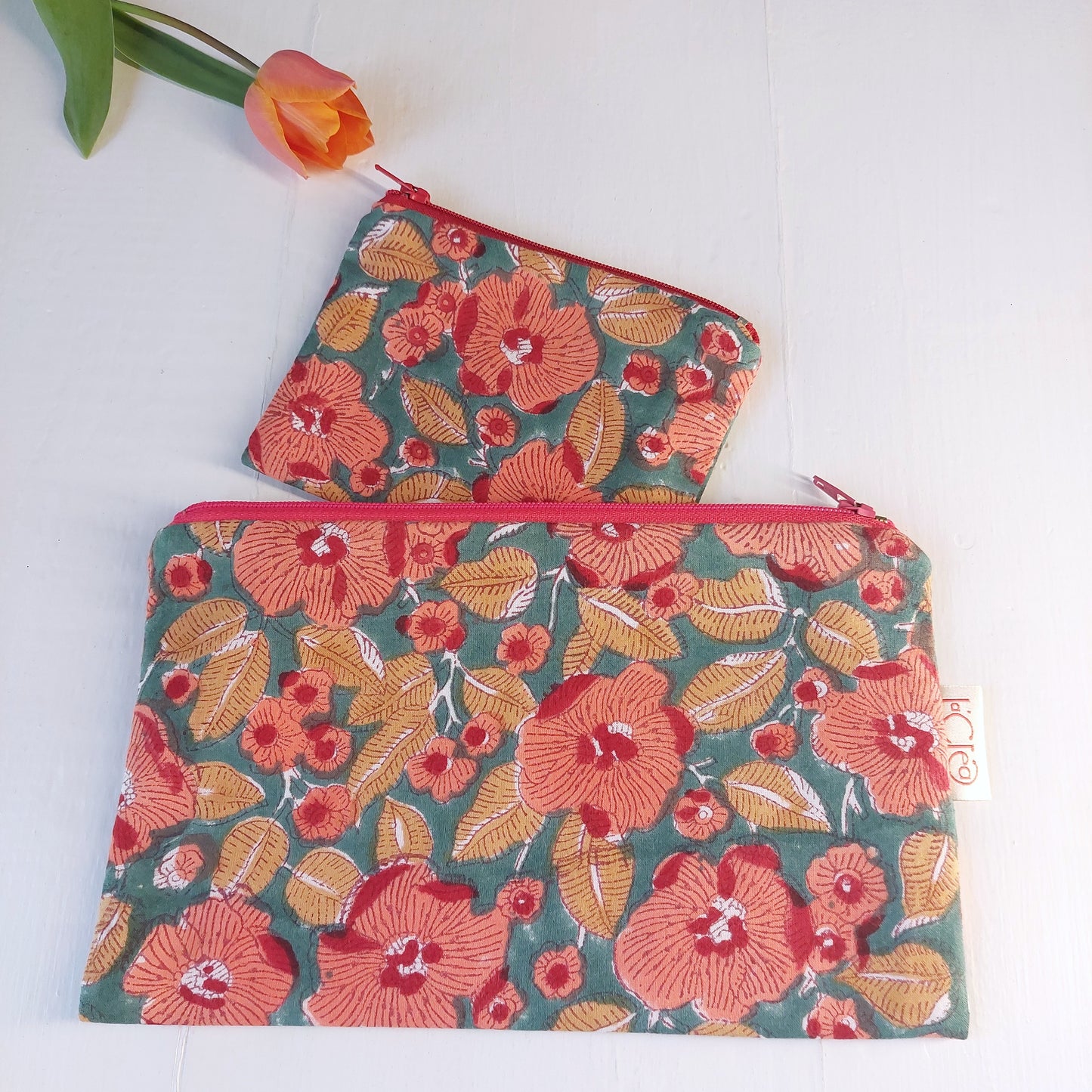 Pochette in cotone verde e rossa con decorazione floreale, foderata.