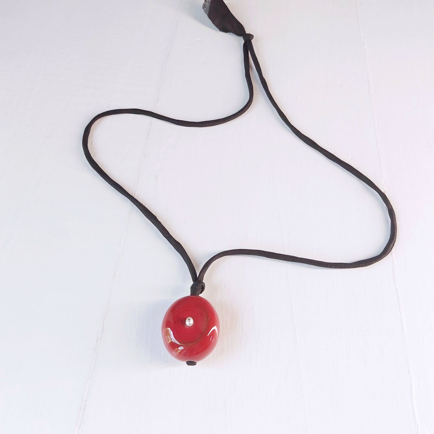 Collana Milu con perla in ceramica rossa, piccola madreperla e laccio in seta nero.