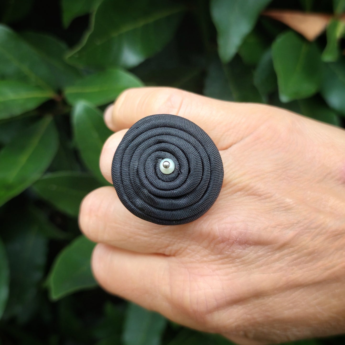 Anello bombato in tessuto verde con piccola perla bianca.