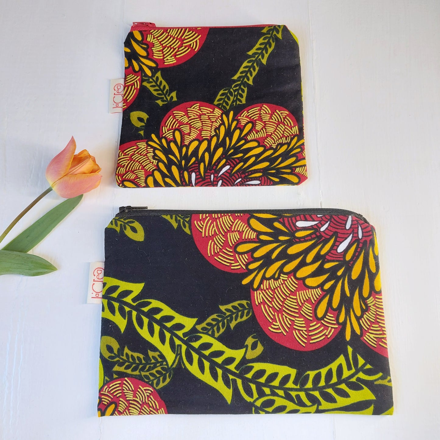 Pochette in cotone con decorazione floreale nero, verde, rosso e giallo, foderata.