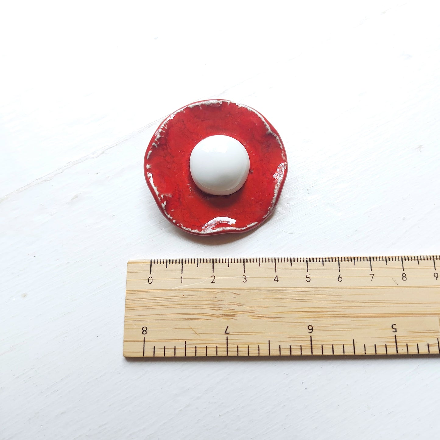 Spilla Bon Bon in ceramica rossa e bianca, con base in metallo.