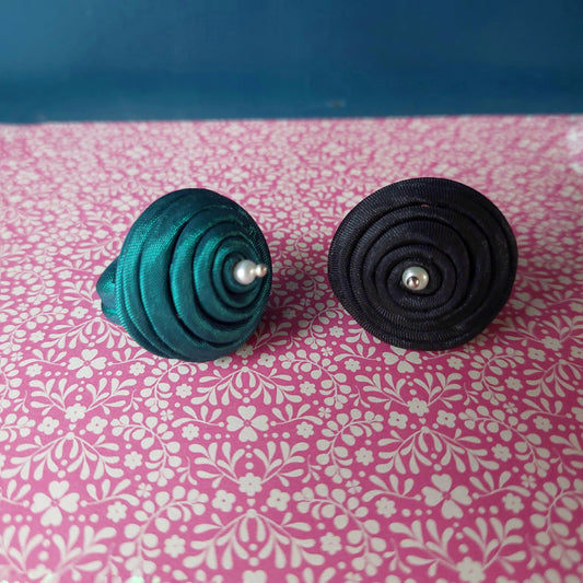 Anello bombato in tessuto verde con piccola perla bianca.