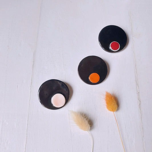 Spilla nera e rossa in ceramica con chiusura in metallo.