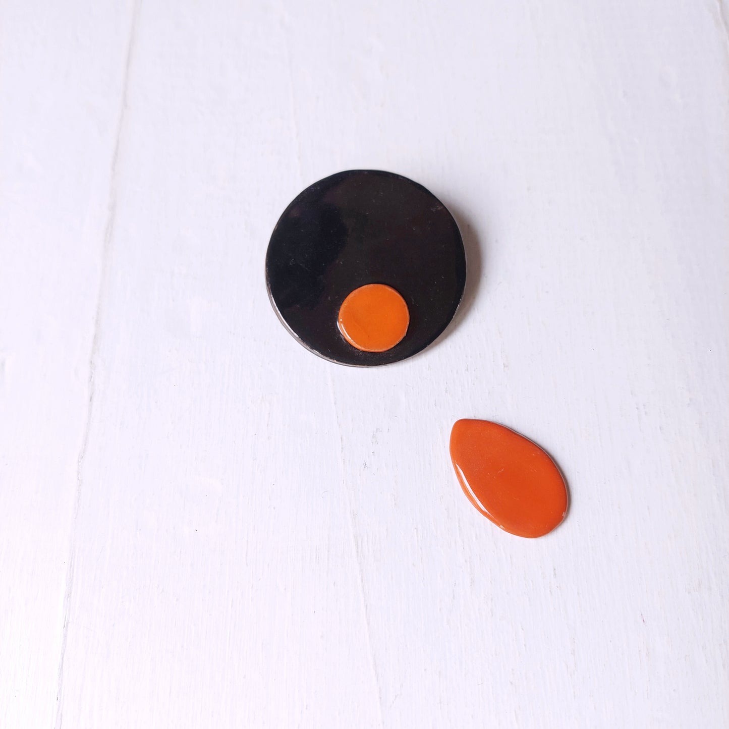 Spilla nera e rossa in ceramica con chiusura in metallo.