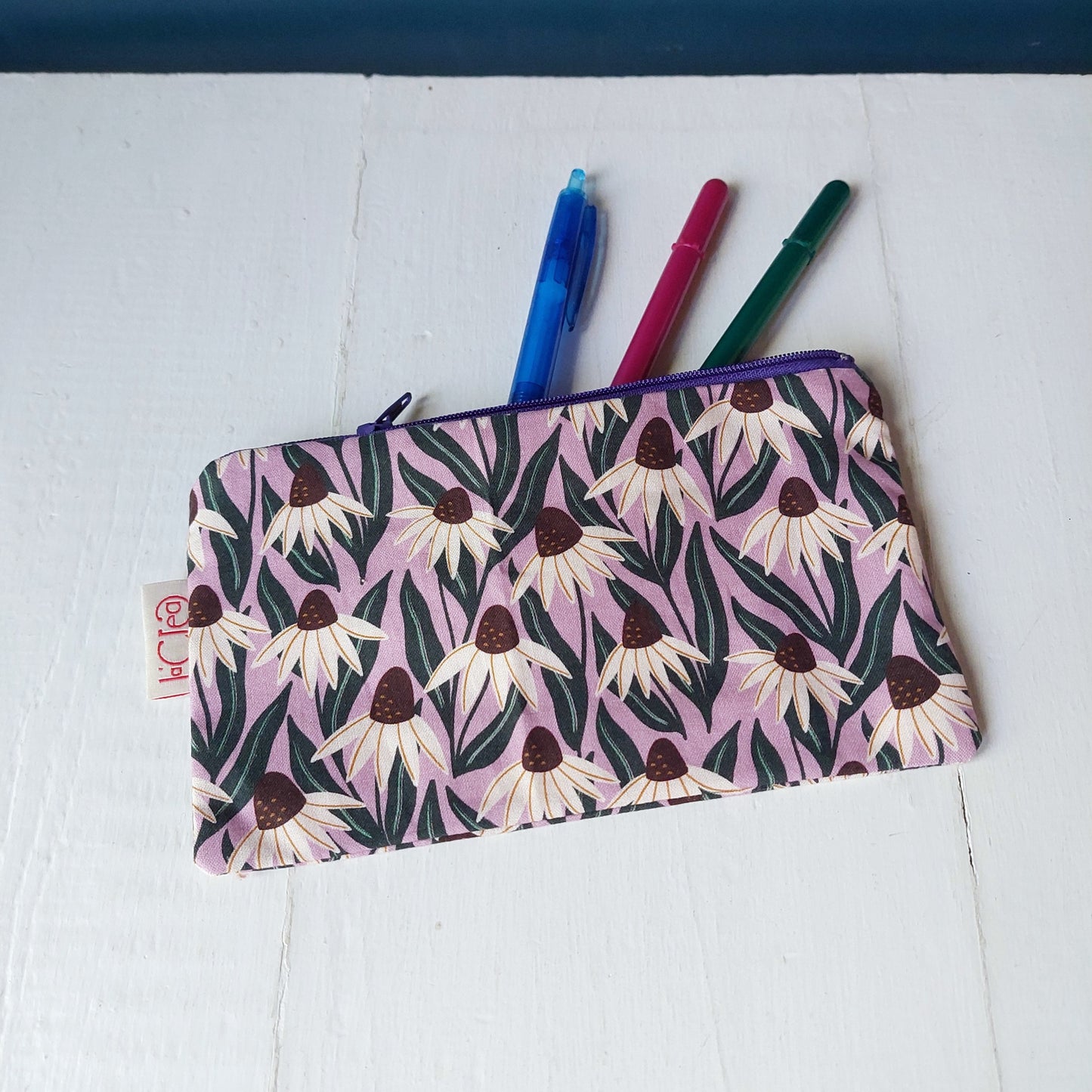 Pochette in cotone viola, bianco e verde con decorazione floreale, foderata.