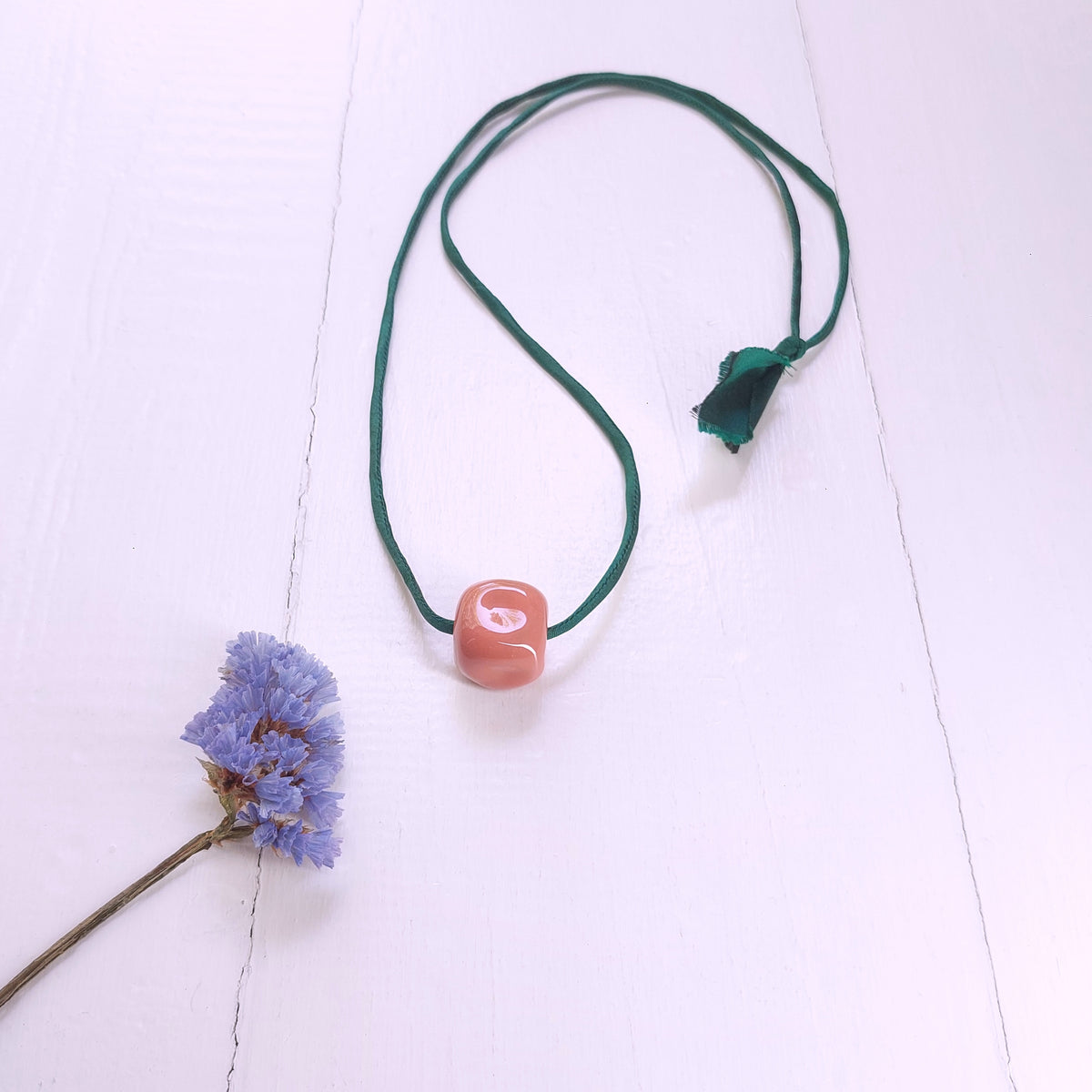 Collana con perla in ceramica rosa e laccio in seta verde .