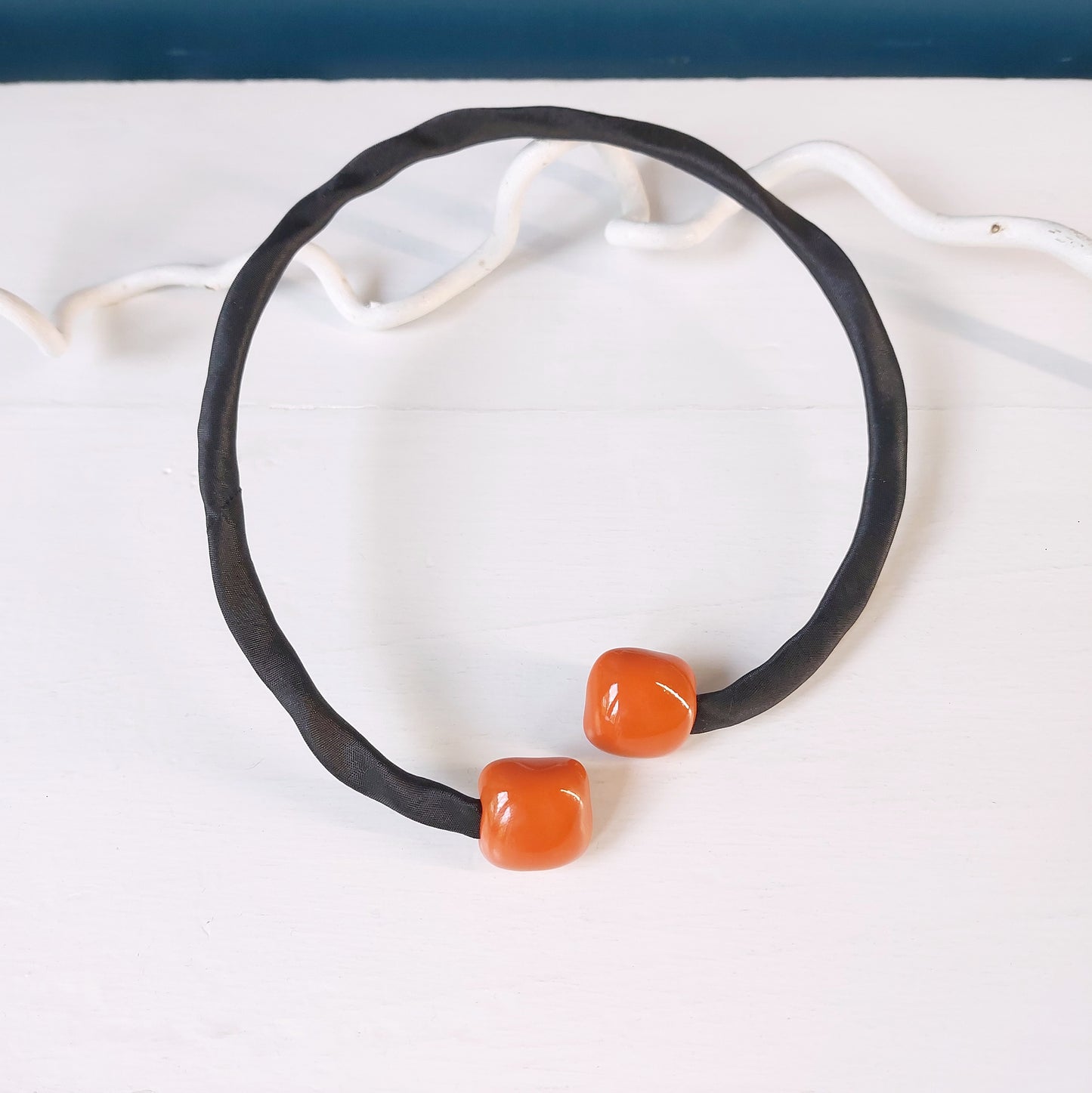 Girocollo con perle rosse quadrate in ceramica e accessorio rigido in metallo ricoperto di tessuto nero, in tre varianti colore.