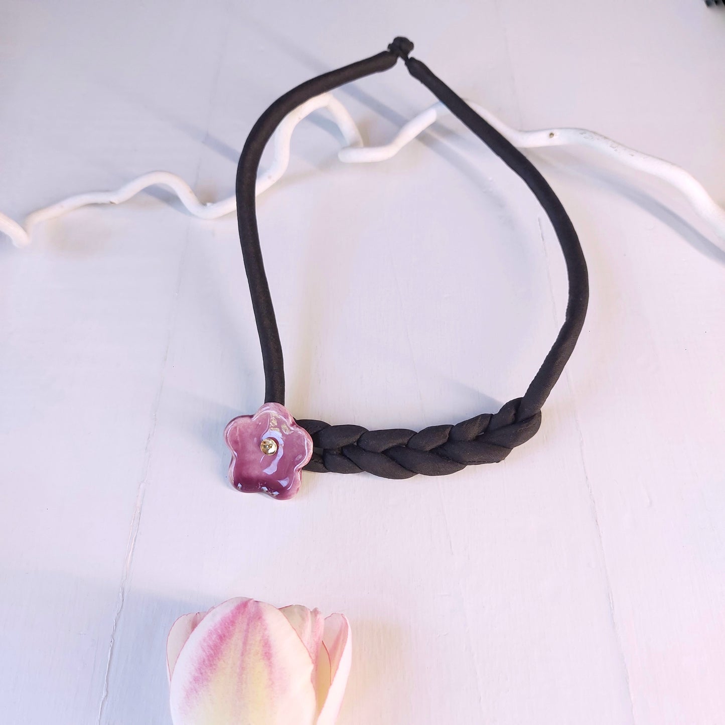 Collana girocollo con fiore viola in ceramica e laccio in seta nera imbottita.