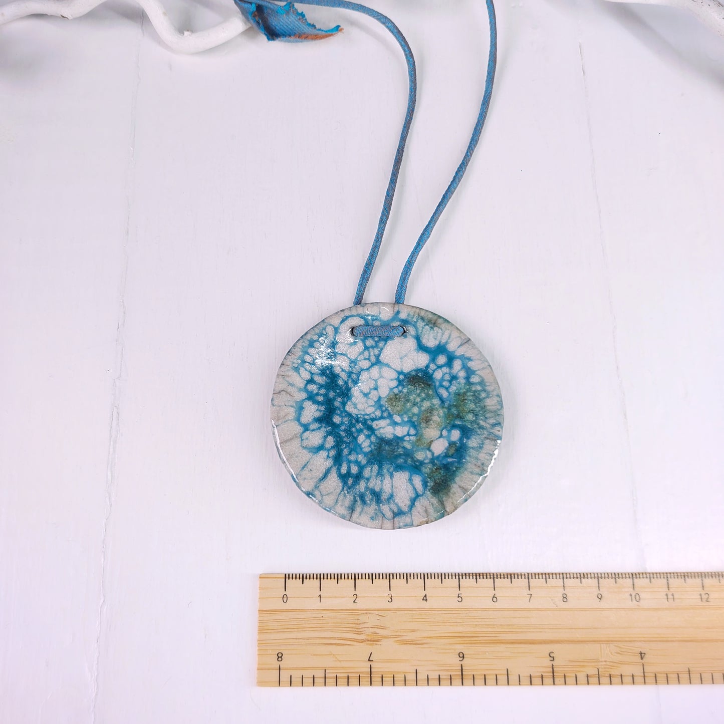 Collana con perla in ceramica bianca e azzurra e laccio in seta azzurra.