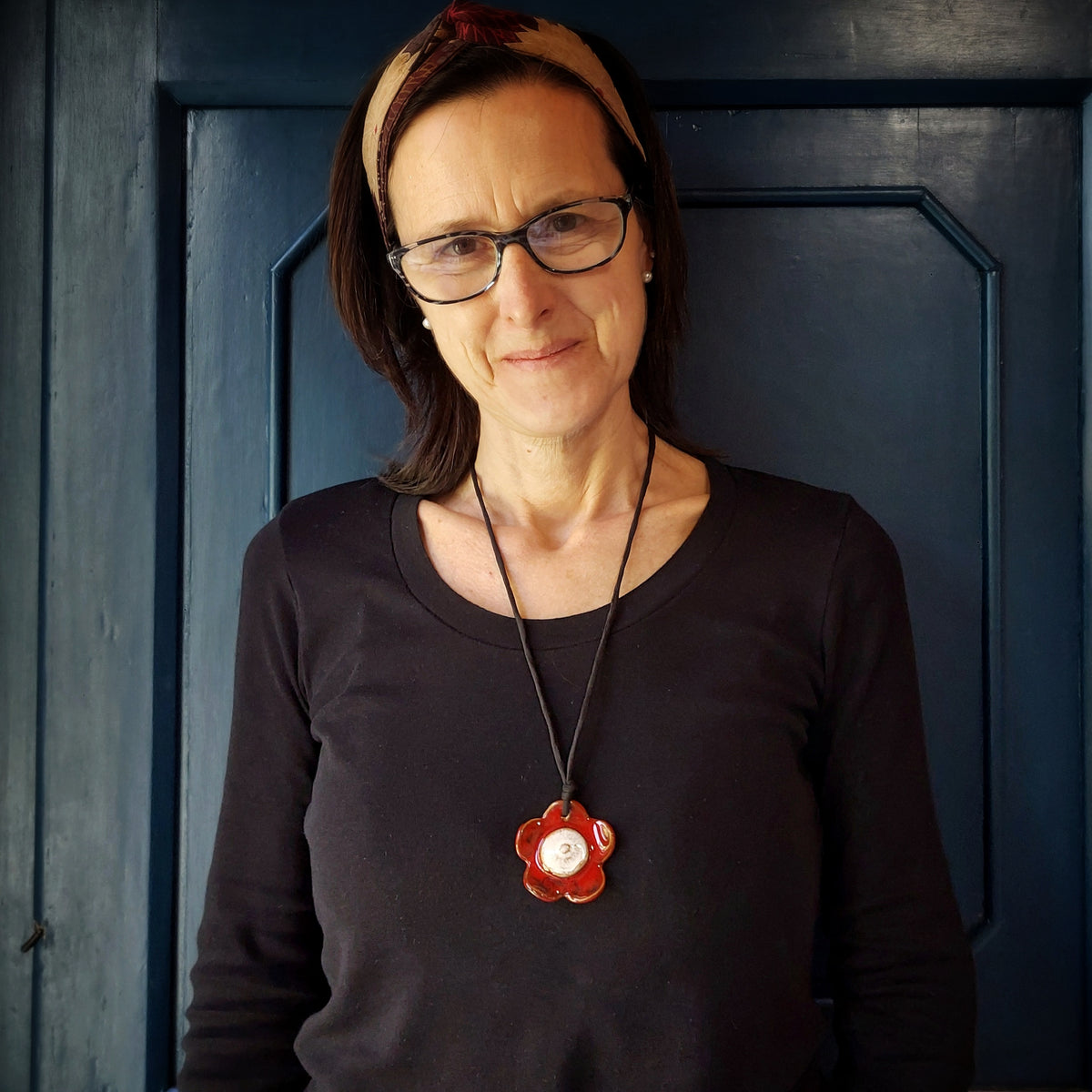 Collana con fiore in ceramica rossa e bianca e laccio in seta nera.
