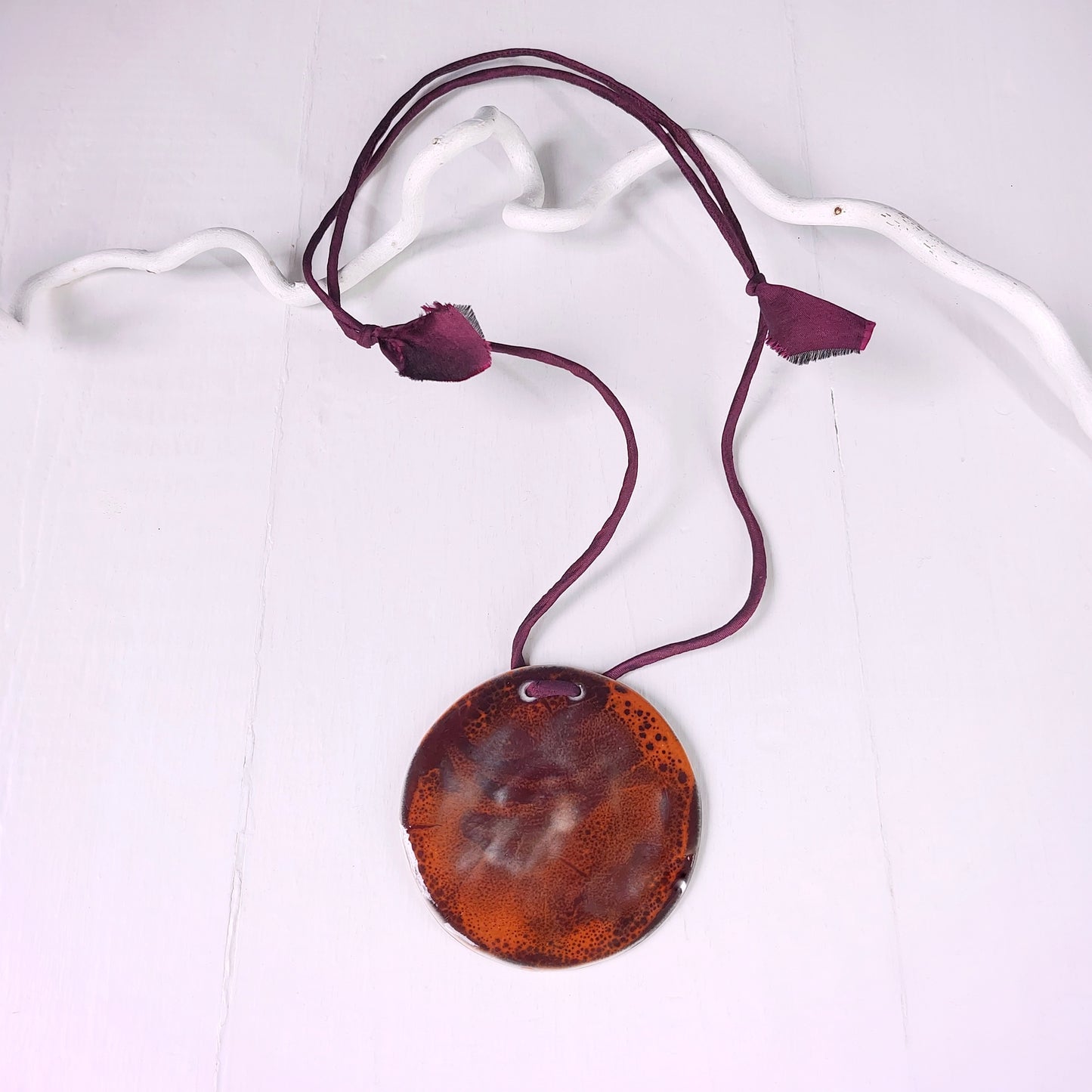 Collana con ciondolo in ceramica rossa e arancione e laccio in seta bordeaux.