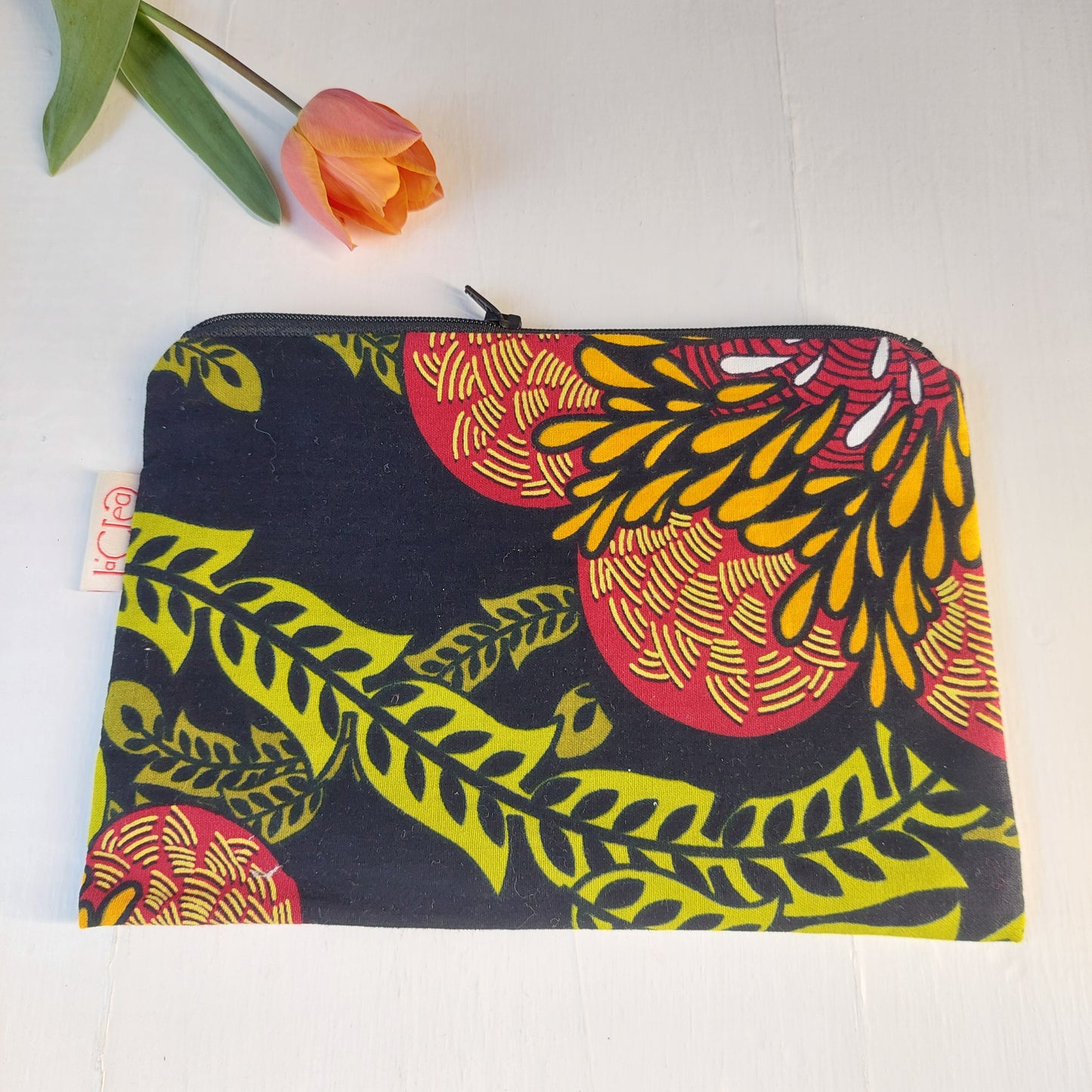 Pochette in cotone con decorazione floreale nero, verde, rosso e giallo, foderata.