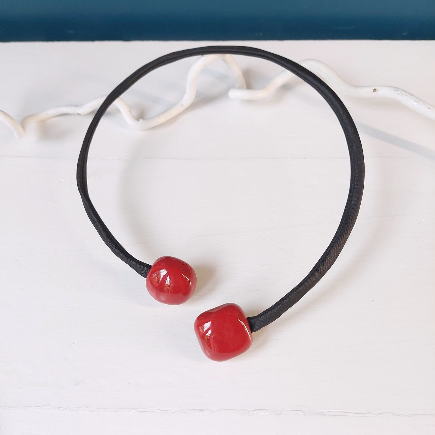Girocollo con perle rosse quadrate in ceramica e accessorio rigido in metallo ricoperto di tessuto nero, in tre varianti colore.