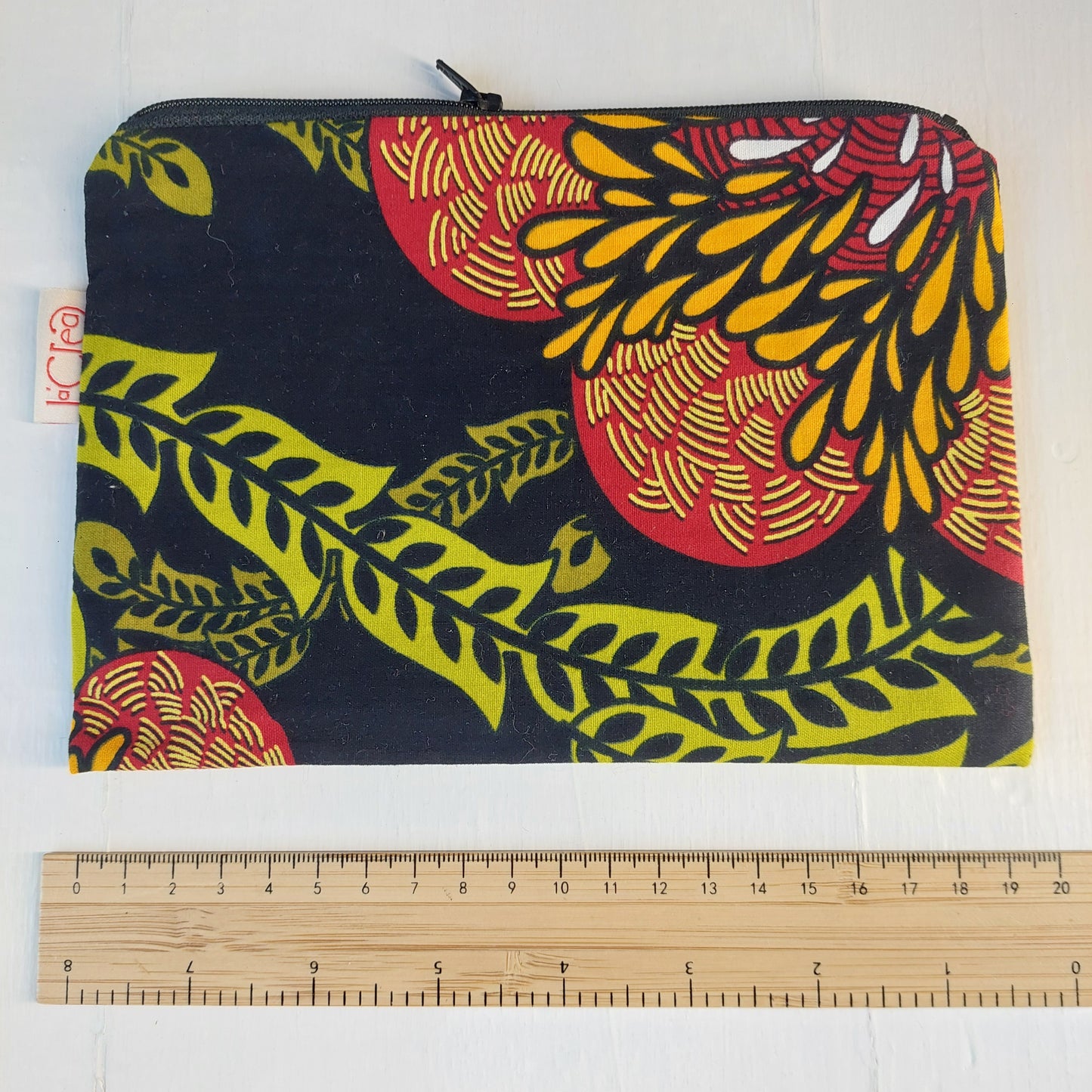 Pochette in cotone con decorazione floreale nero, verde, rosso e giallo, foderata.
