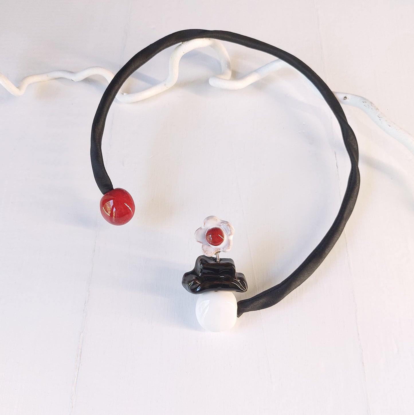 Girocollo Mary Poppins con perle rosse, bianche e nere in ceramica e accessorio rigido in metallo ricoperto da tessuto nero.