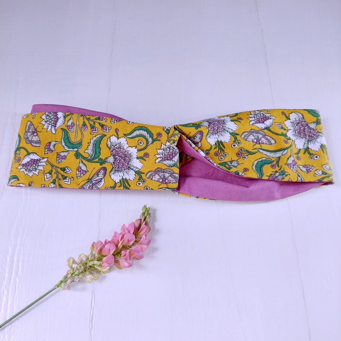 Fascia per capelli fantasia floreale gialla e viola con chiusura ad elastico.