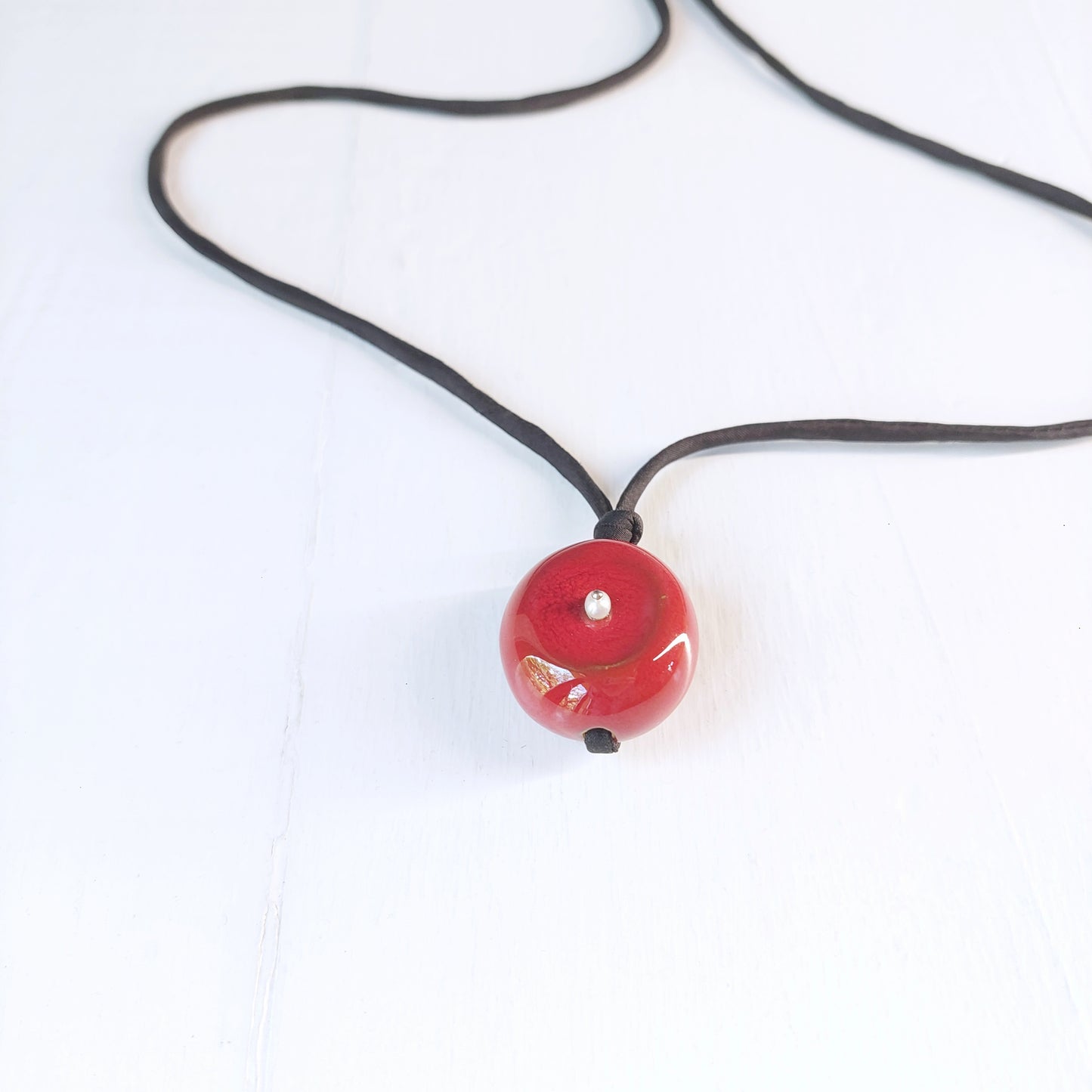 Collana Milu con perla in ceramica rossa, piccola madreperla e laccio in seta nero.
