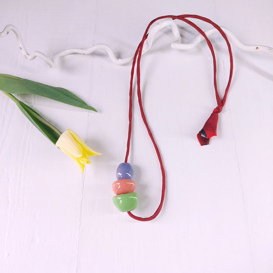 Collana da donna con tre perle in ceramica verde, rosa, viola e laccio in seta bordeaux.