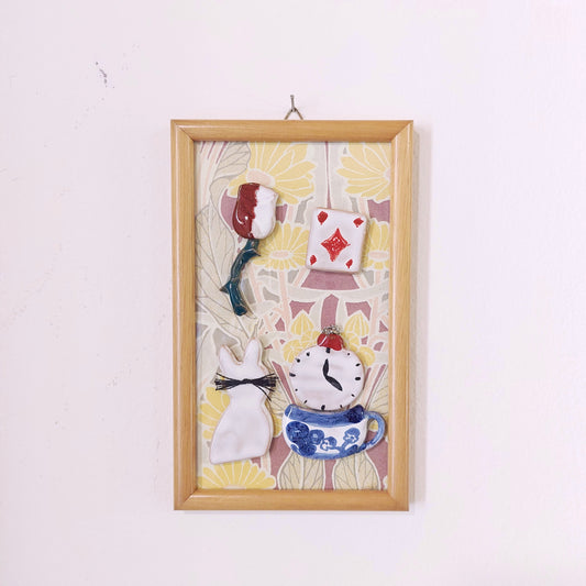 Quadro con ceramiche ispirate ad Alice nel Paese delle Meraviglie e cornice in legno.