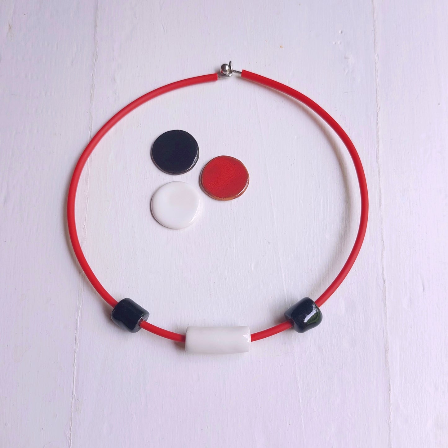 Collana girocollo rigido donna con perle rosse e bianche in ceramica ed accessorio in metallo rivestito da caucciù rosso.