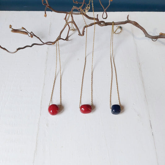 Collana girocollo con perla in ceramica rossa e catena color oro, in tre varianti.