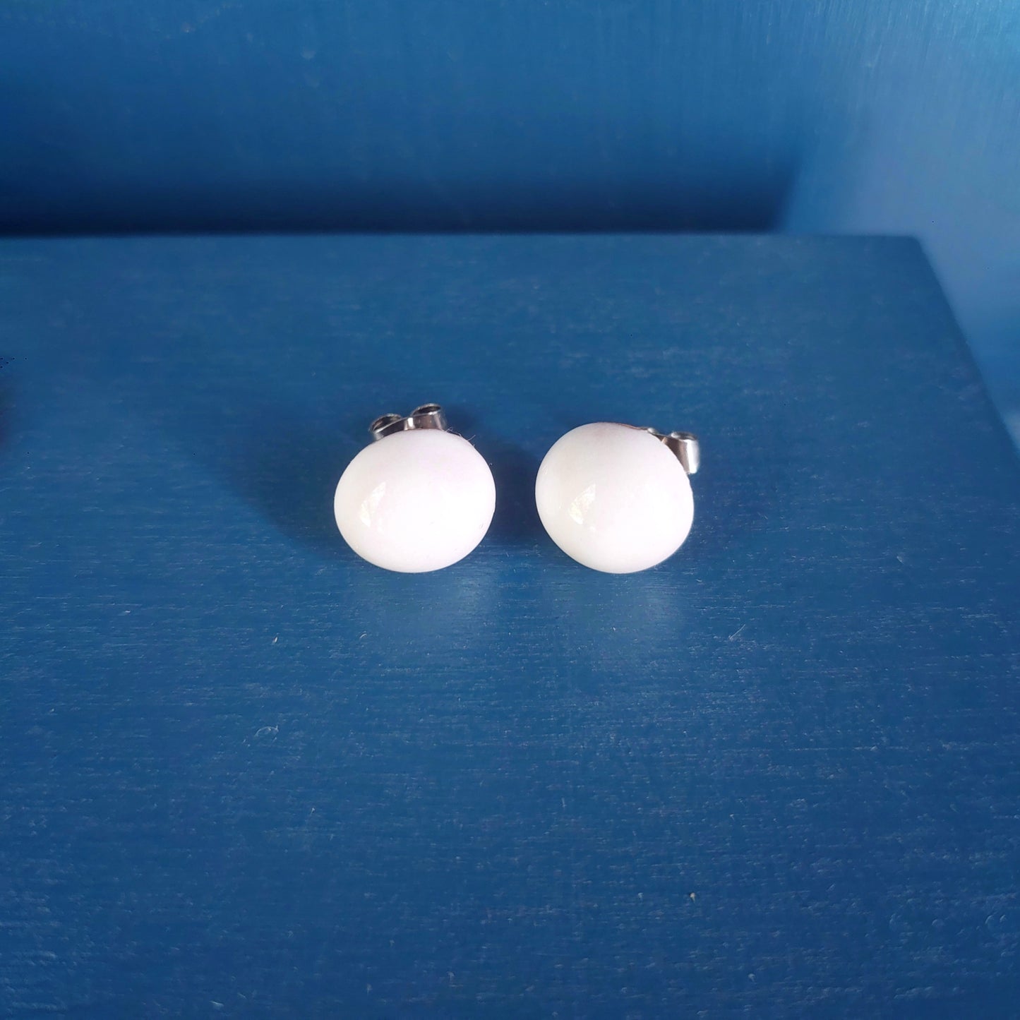 Orecchini bombati con perla in ceramica rossa in quattro varianti colore.