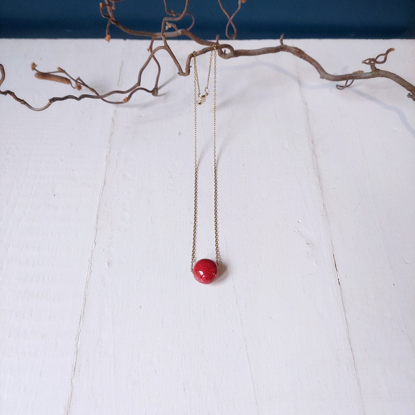 Collana girocollo con perla in ceramica rossa e catena color oro, in tre varianti.